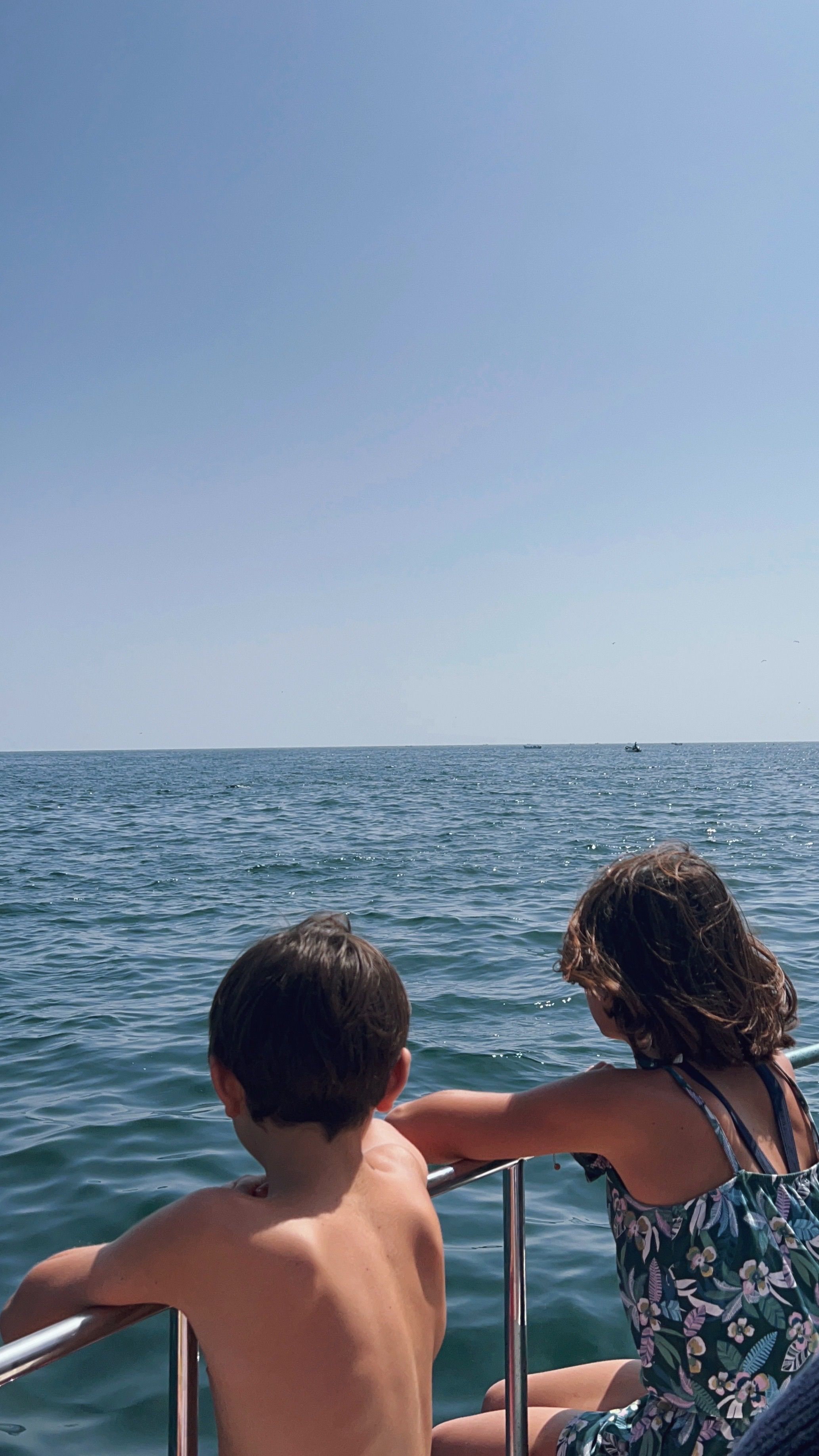 Two children leaning on the rail of a motor yacht, looking out over open South Florida sea